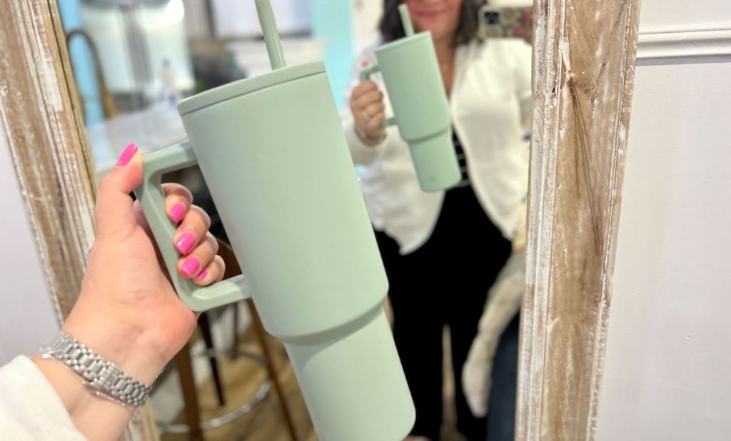 woman holding blue matte tumbler in front of mirror