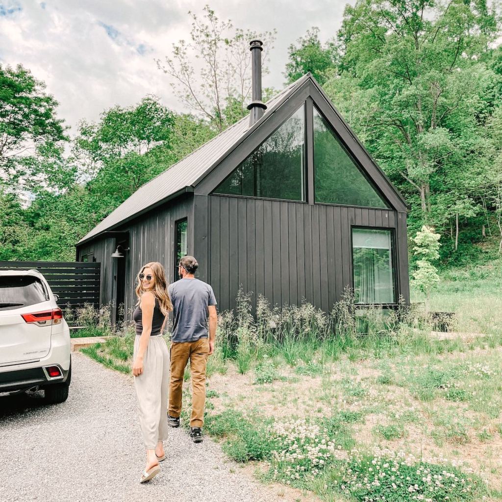 couple holding hands in front of black modern tiny house