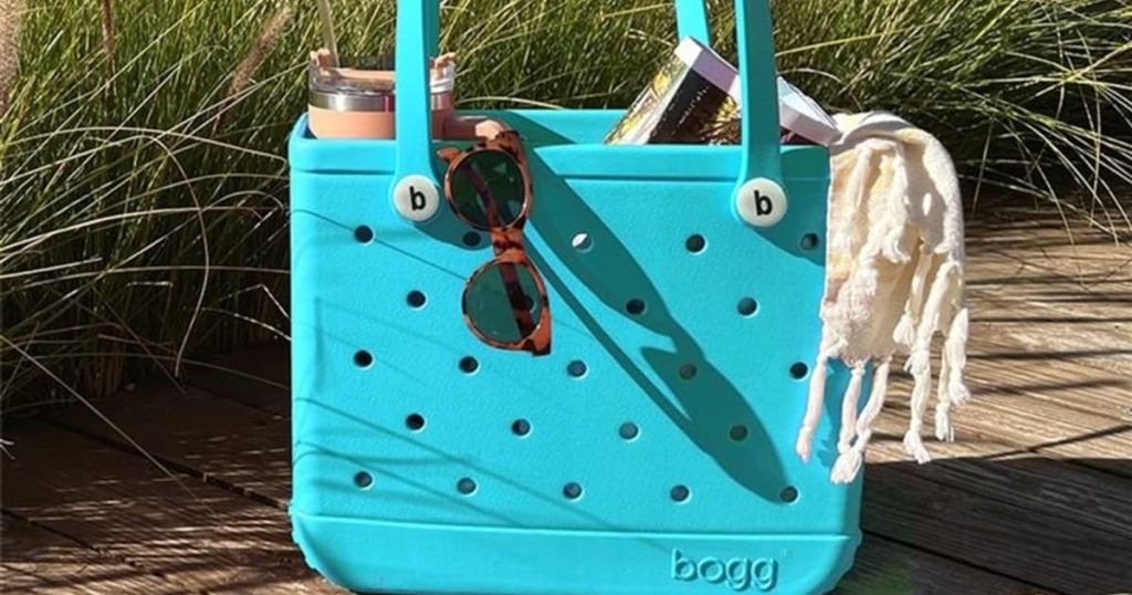baby bogg bag in blue with sunglasses and other accessories