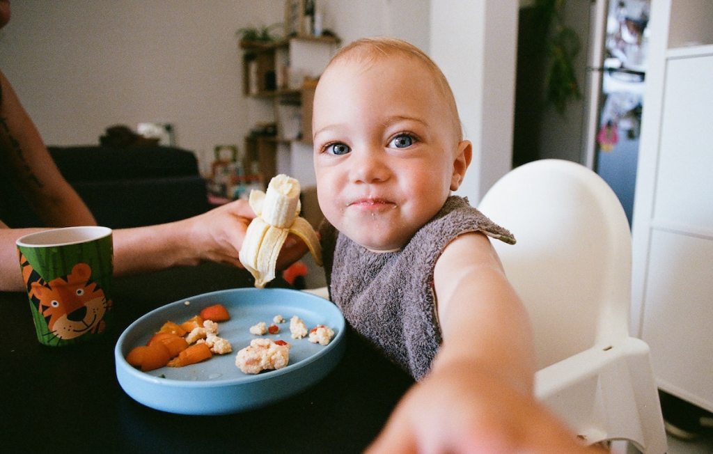 big blue eyed baby sitting in an airbnb essentials highchair eating