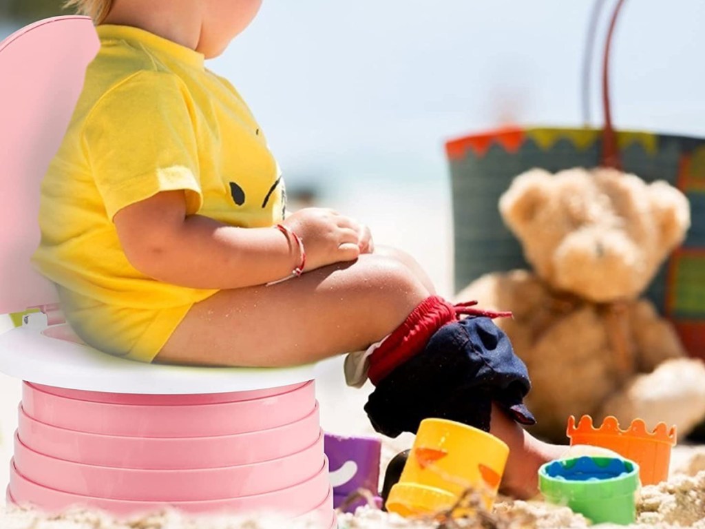 baby using potty seat on the beach