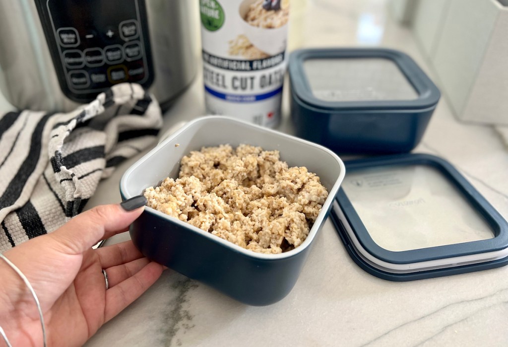 hand holding navy blue container with steel cut oats inside