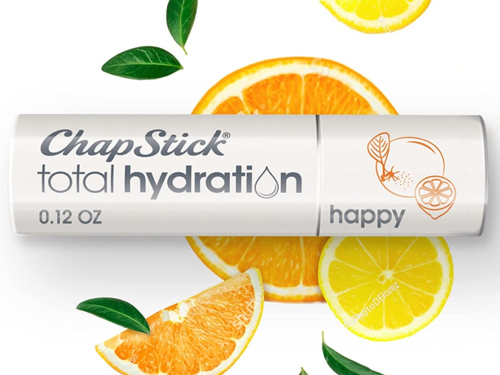 stock image of a tube of chapstick total hydration happy lip balm with orange slices and leaves in the background