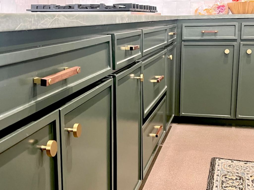 close up of green kitchen cabinets with gold hardware