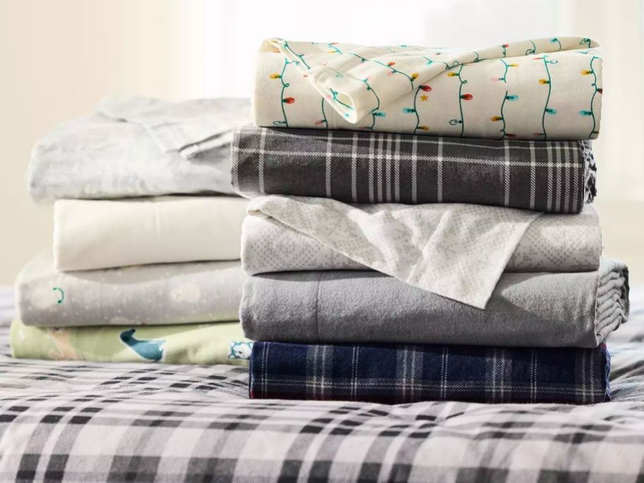 various flannel sheet sets folded and sitting on bed
