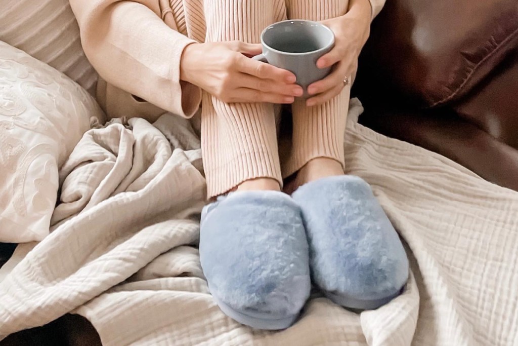 hands holding coffee wearing pair of slippers