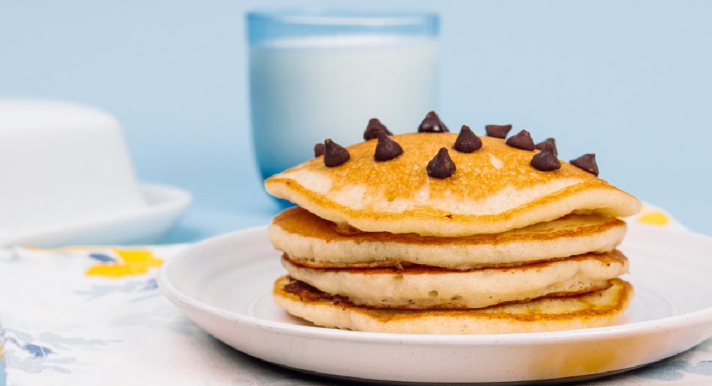 stack of pancakes next to glass of milk 