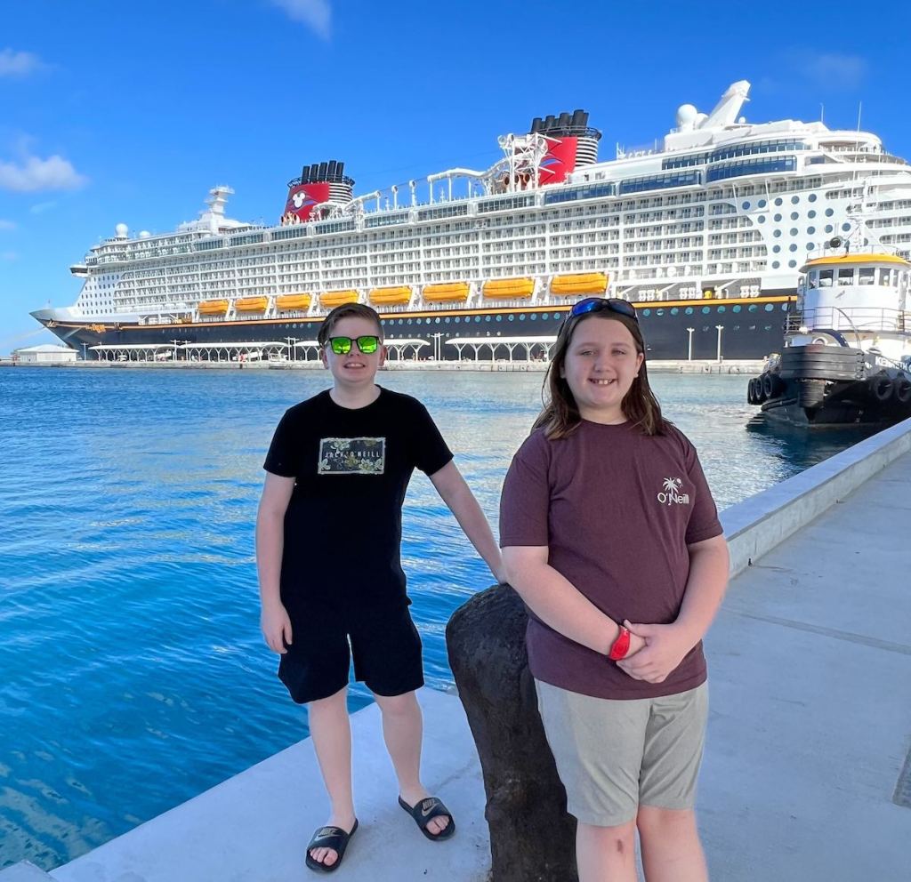 kids standing on pier with disney cruise ship in background