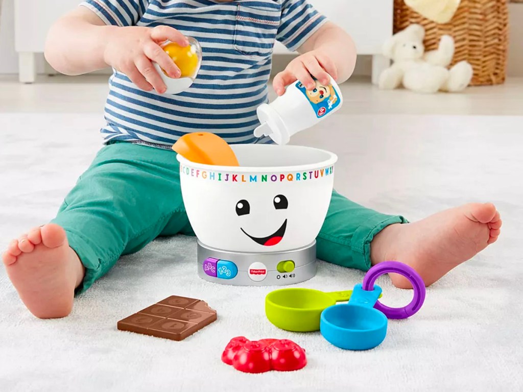 child playing with fisher price mixing bowl toy, pouring ingredients into a bowl