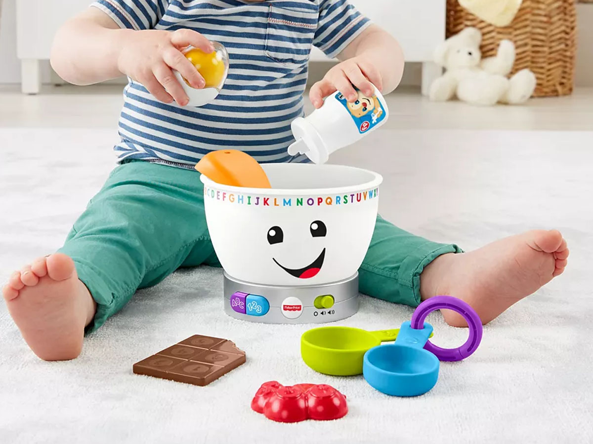 child playing with fisher price mixing bowl toy, pouring ingredients into a bowl