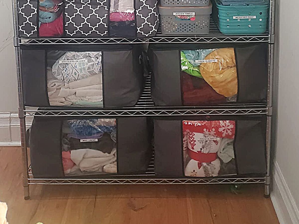 four large storage bags filled with clothes and bedding stored on a wire shelving unit