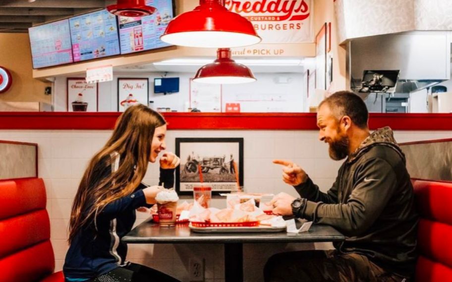 child and man sitting in booth at freddy's eating 