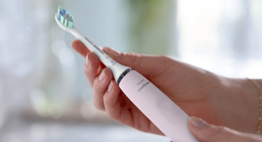 hand holding sonic toothbrush in pink