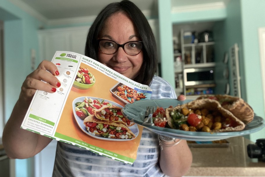 woman holding recipe card and plate of pitas