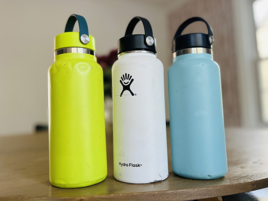 green white and blue hydro flask water bottles on wood table