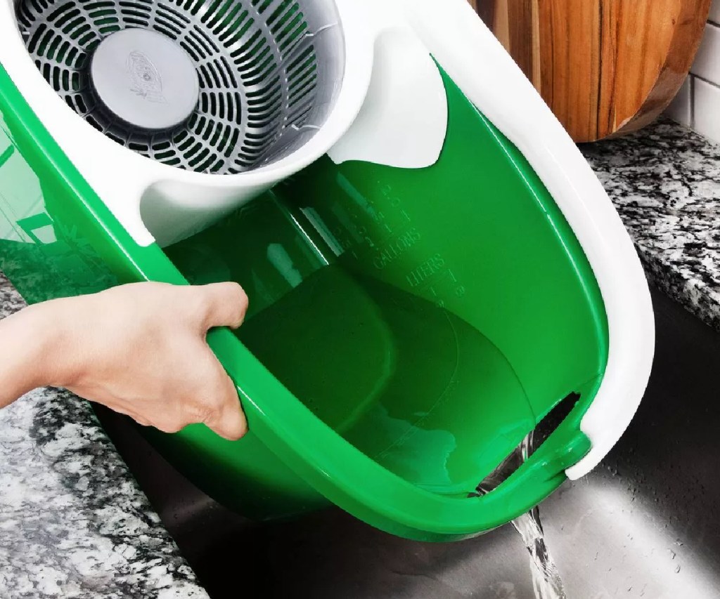 woman puring water from a libman spin mop bucket down the sink