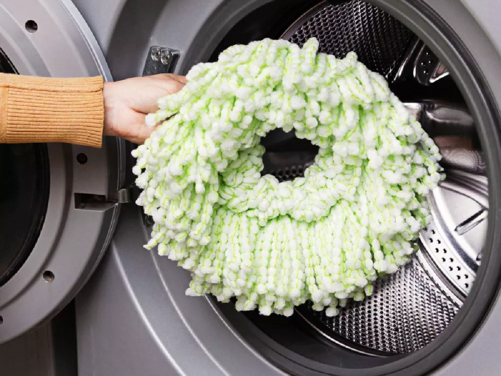 woman putting a libman spin mop head in a washing machine