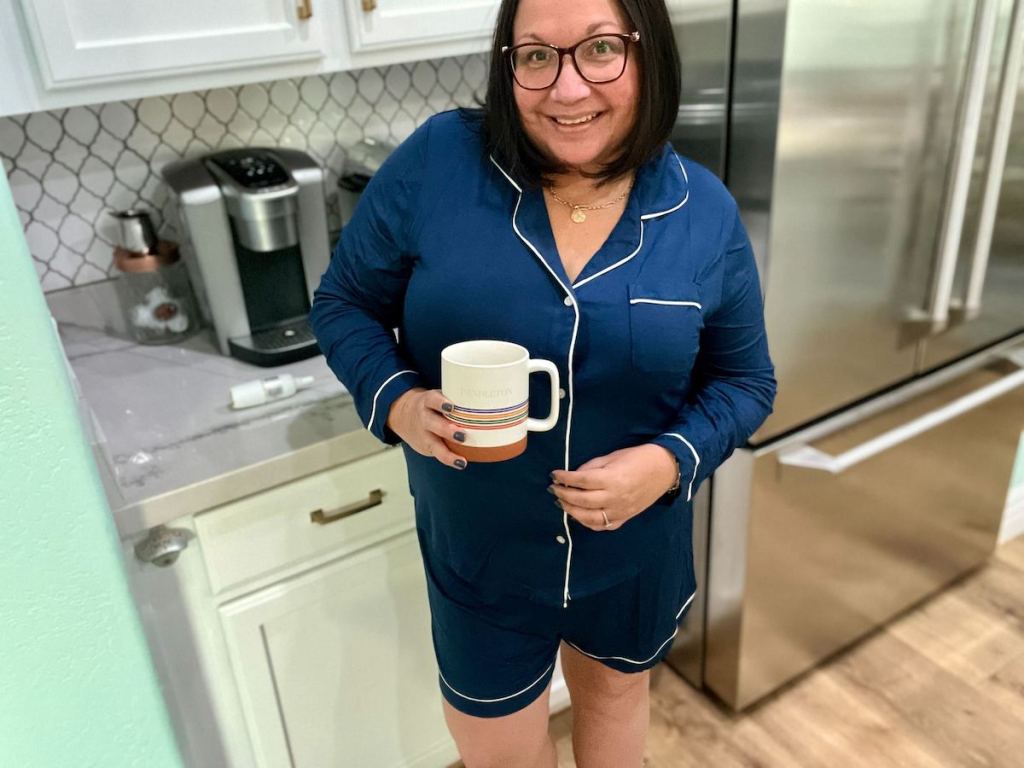 women holding coffee mug wearing navy pajamas in kitchen
