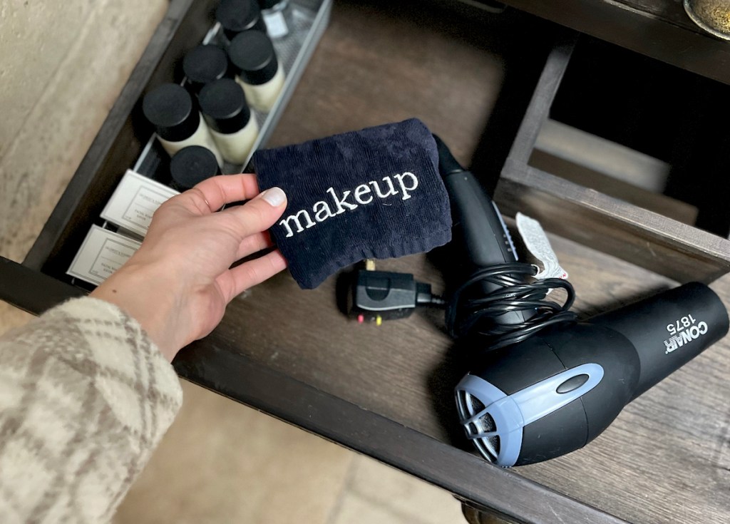 hand holding a black airbnb essentials makeup towel in vanity drawer