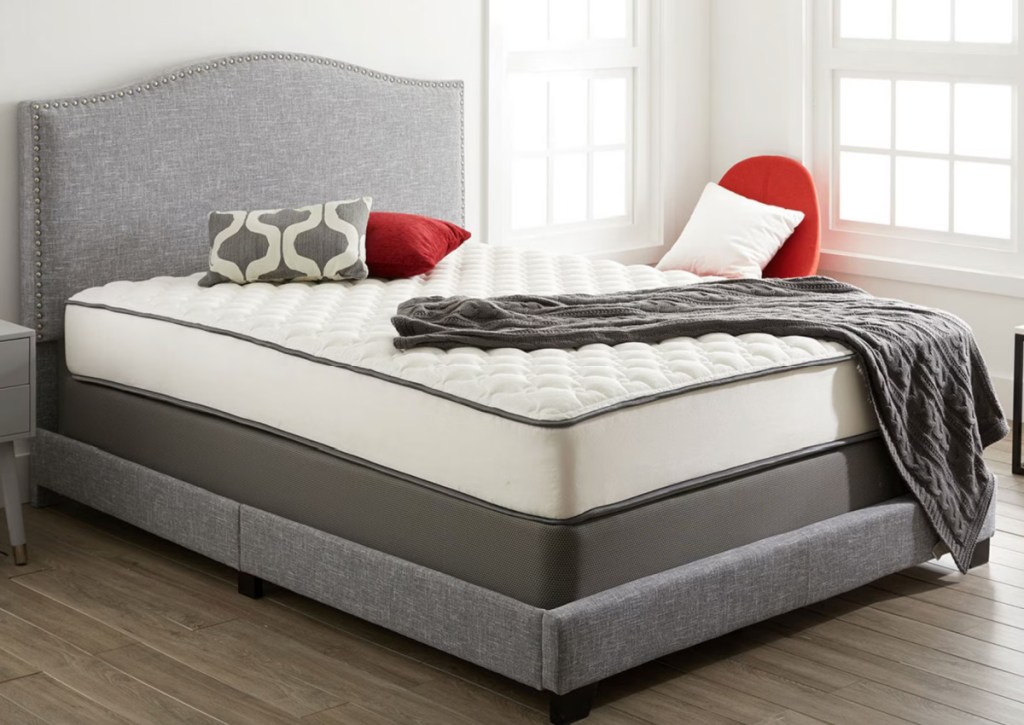beautyrest mattress with fabric headboard and red pillows