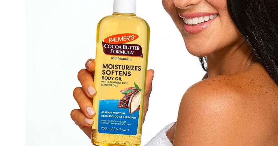 woman holding a bottle of Palmer's cocoa butter oil 