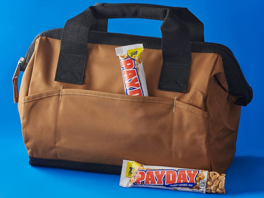 work satchel with a payday candy bar tucked into the front pocket and one sitting in front of it