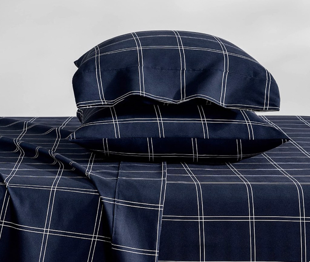 stock photo of navy blue plaid sheets on bed with two pillows stacked on top of each other