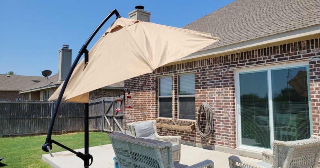tan umbrella hanging over patio set in back of brick house
