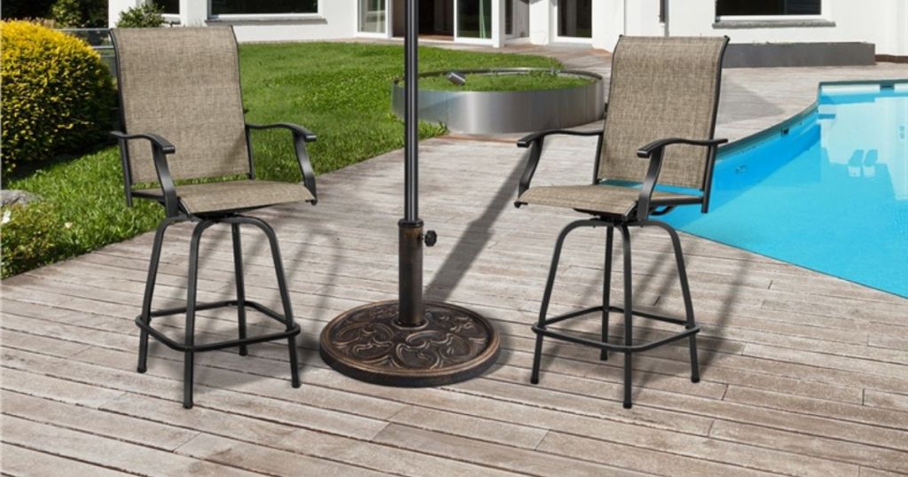 bronze umbrella base with 2 chairs on either side and pool in background