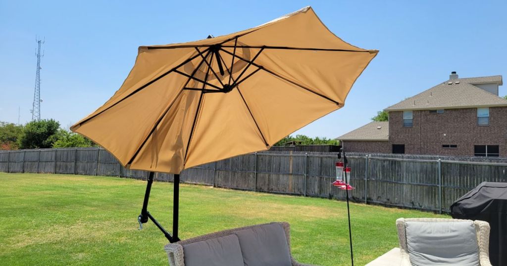 tan umbrella in the backyard over patio set