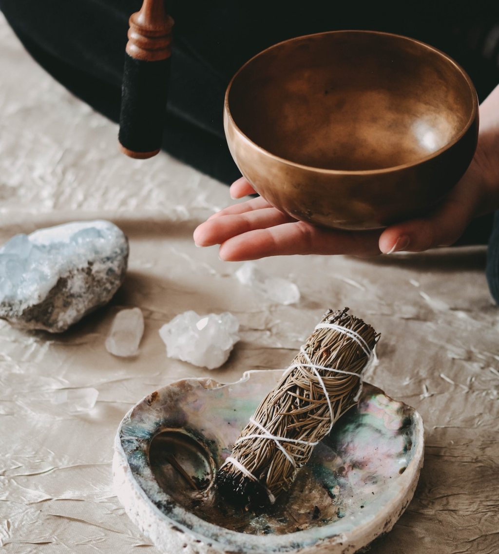 hand holding a sound healing bowl over dried sage