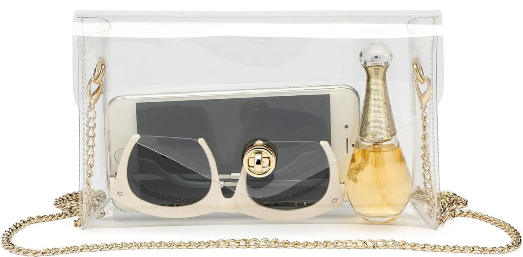 stock image of Vorspack Clear Crossbody Bag with sunglasses, cellphone and perfume