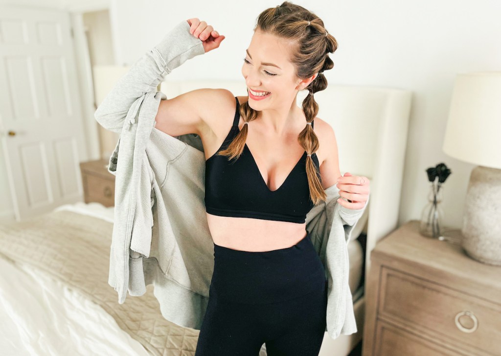 woman laughing wearing gray sweater and black workout clothes