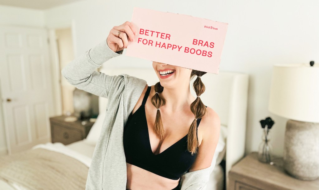 woman holding up pink sign about bras laughing