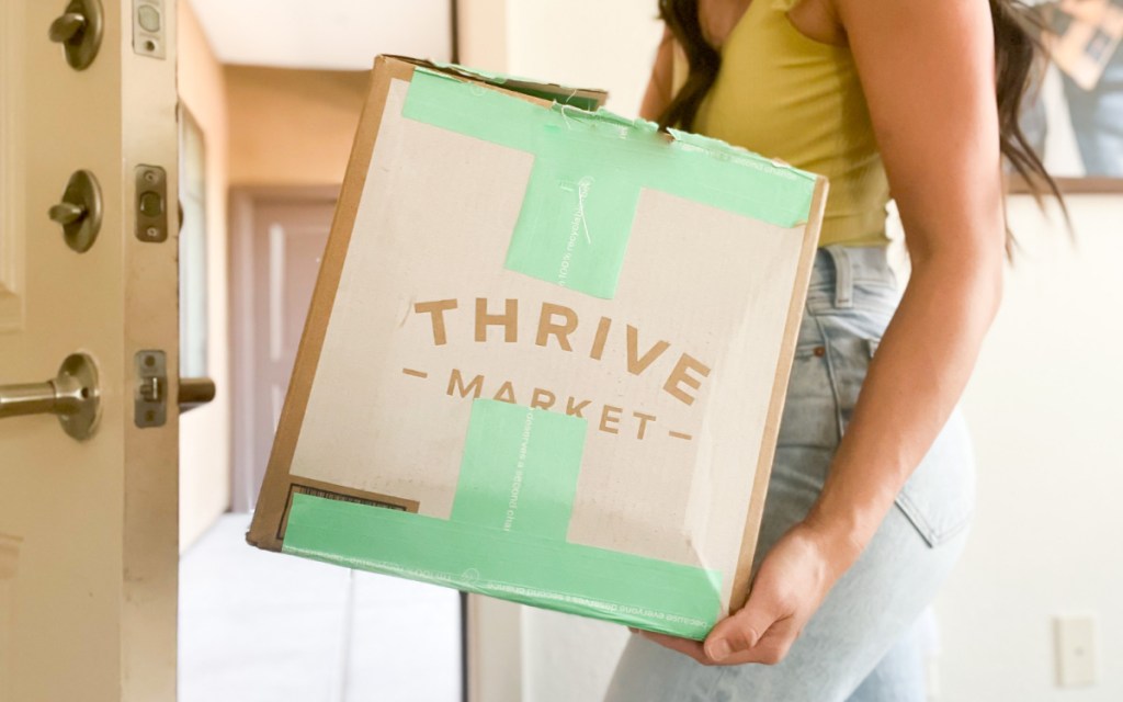 thrive market offers a teacher discount which this woman holding a thrive market box took advantage of