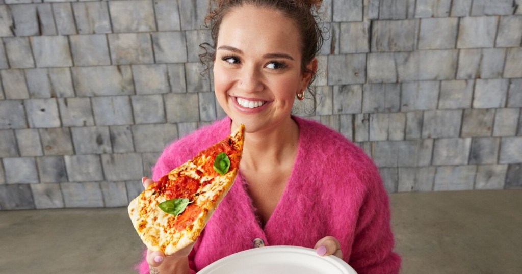 woman holding a pizza slice and a plate