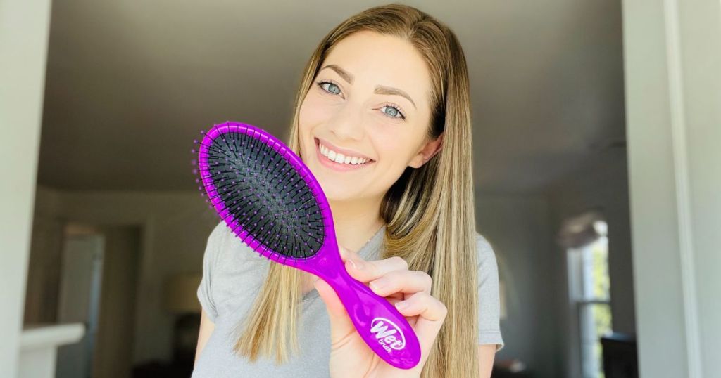 A woman holding a purple hairbrush