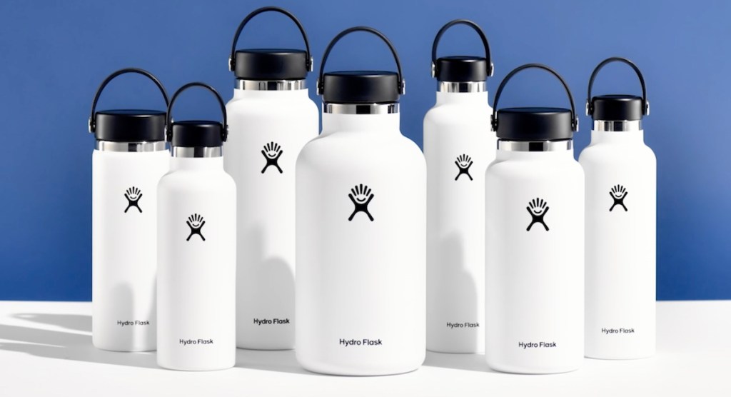 various sizes of white hydro flasks on white table with blue background