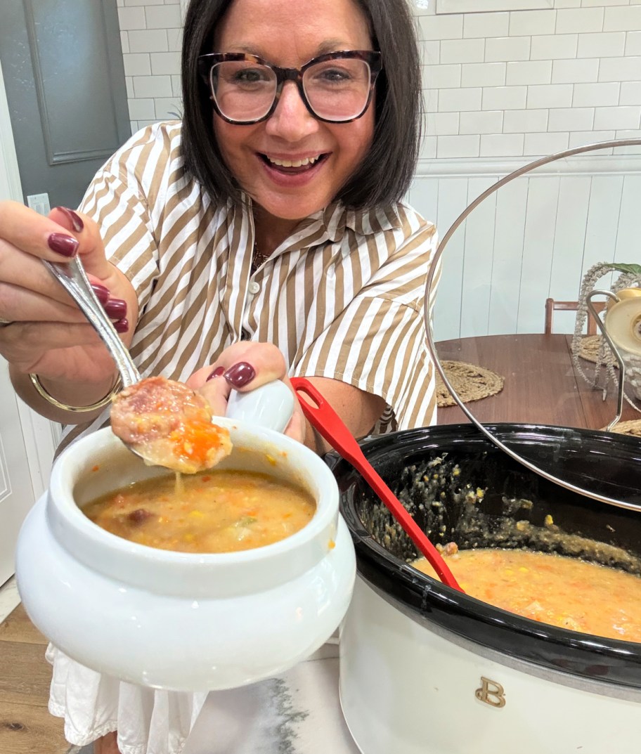 woman holding a bowl of sausage corn chowder 