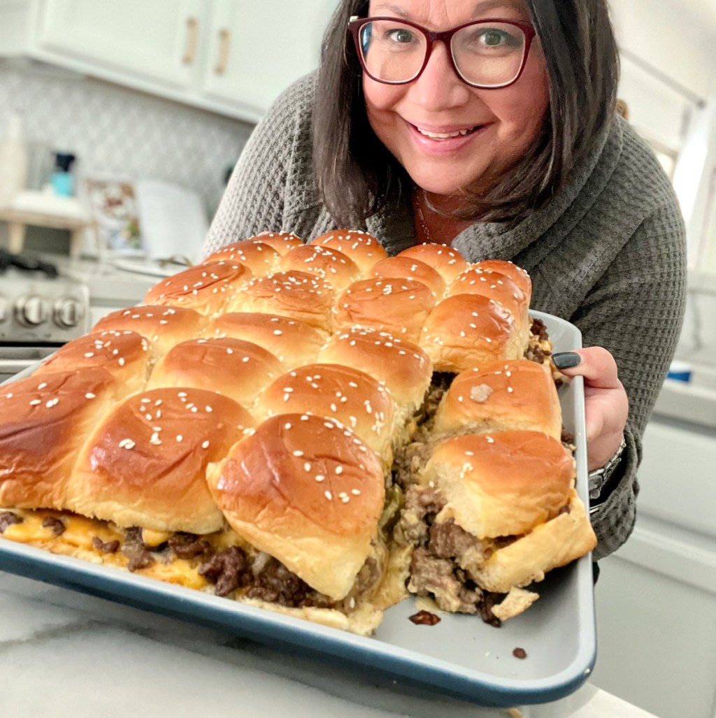 Woman holding a large pan of big mac inspired party sliders.