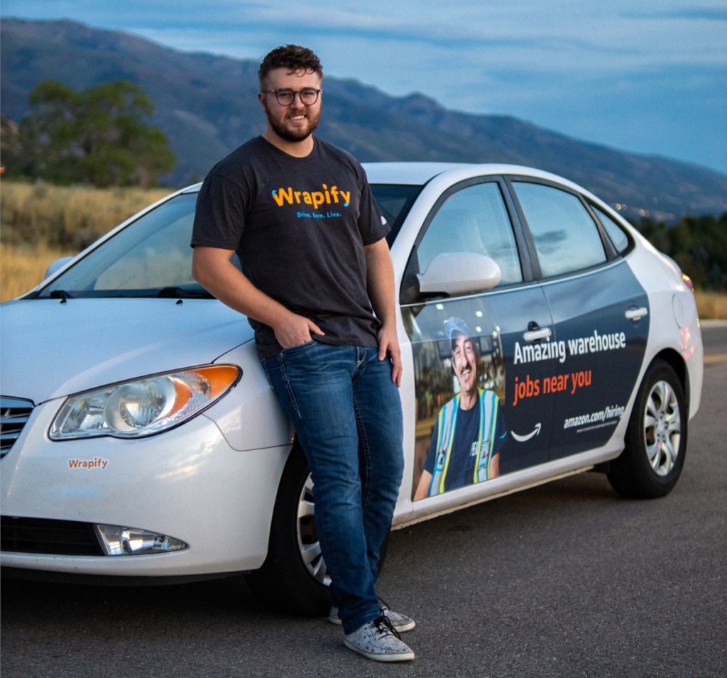 Get paid to advertise on your car like this man standing next to his vehicle with a car wrap advertisement from Wrapify