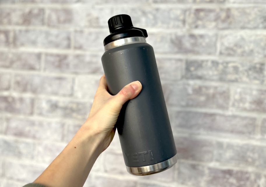 Hand holding a dark gray yeti rambler water bottle