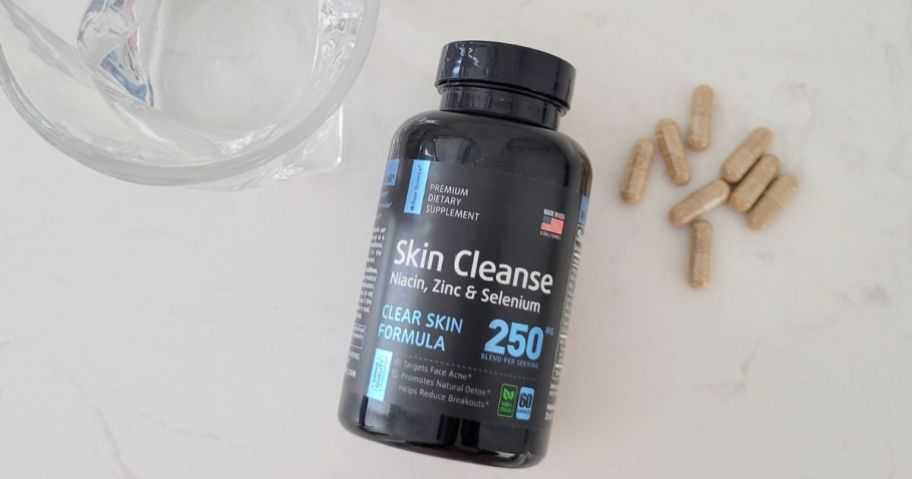 Raw Science Perfect Skin bottle, capsules and a glass of water