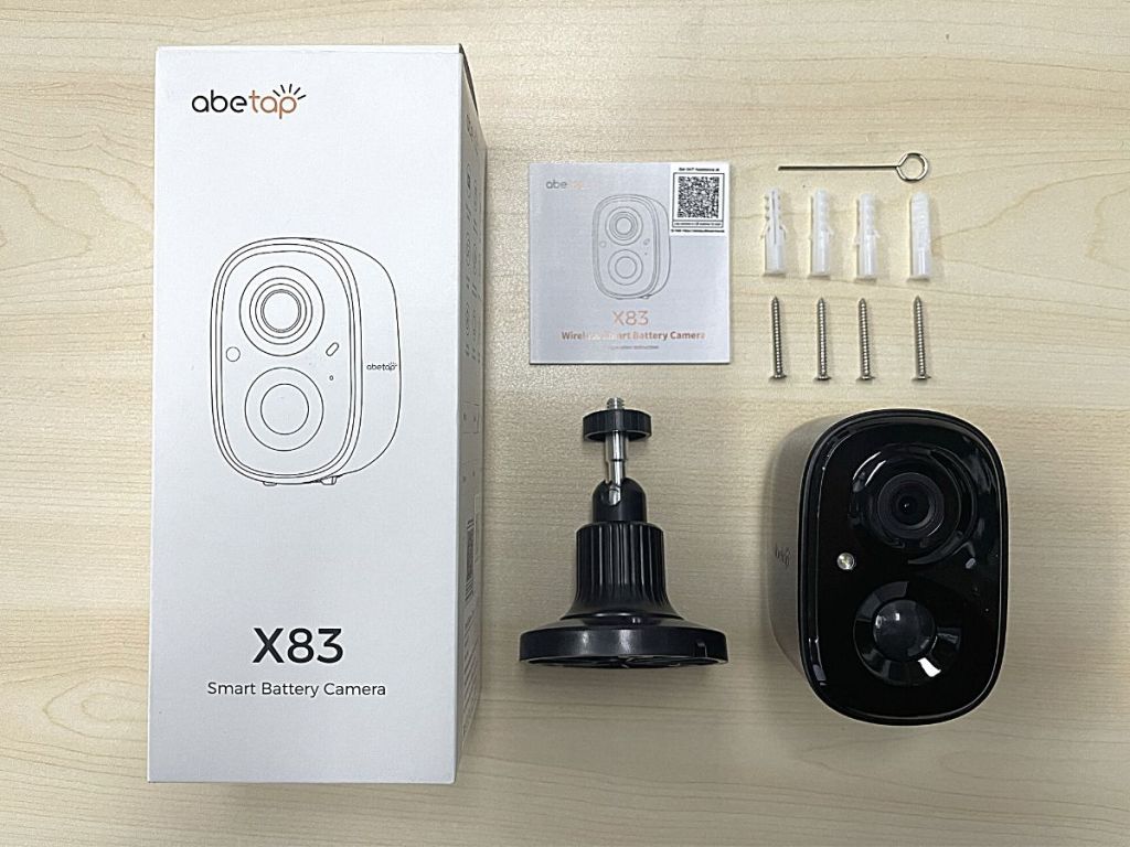 abetap X83 box with black Smart Security camera and accessories laid out on table beside box