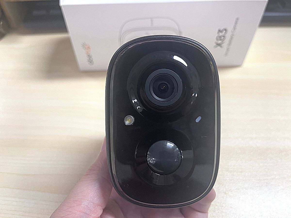 hand holding black security camera with packaging in background