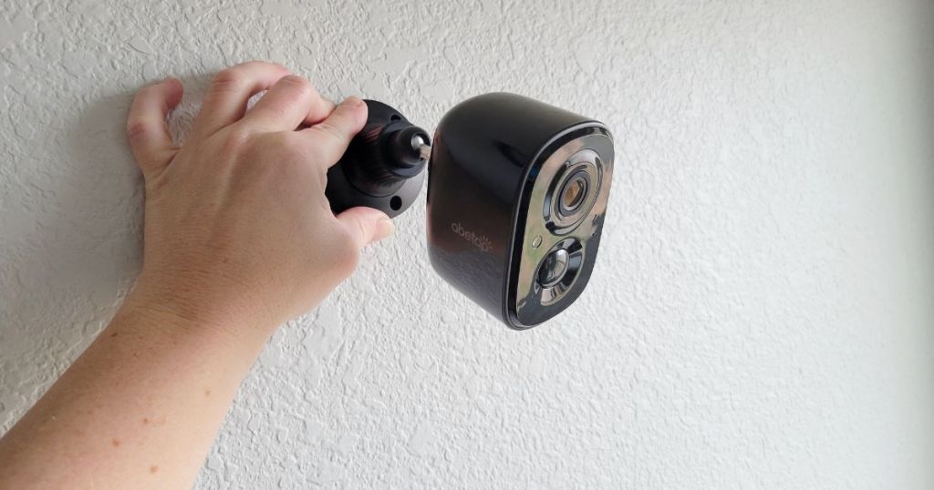 hand holding a security camera to the wall