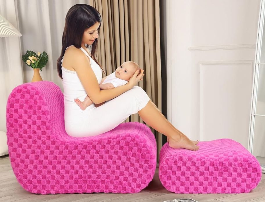 a woman holding a baby sitting on a pink beanbag chair