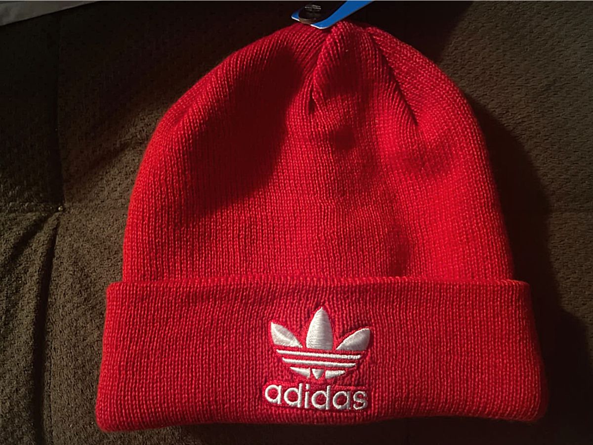 red and white adidas beanie on black bedding