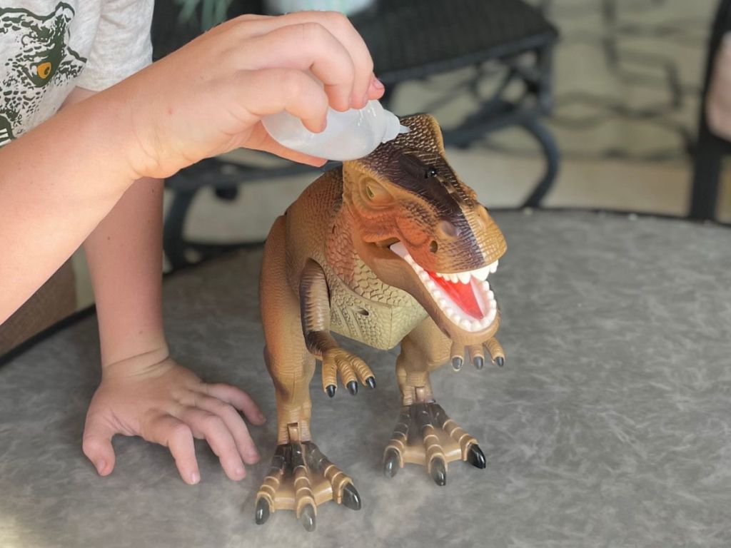 boy using the water bottle to put water in the top of the Advanced Play Dinosaur Trex Toy