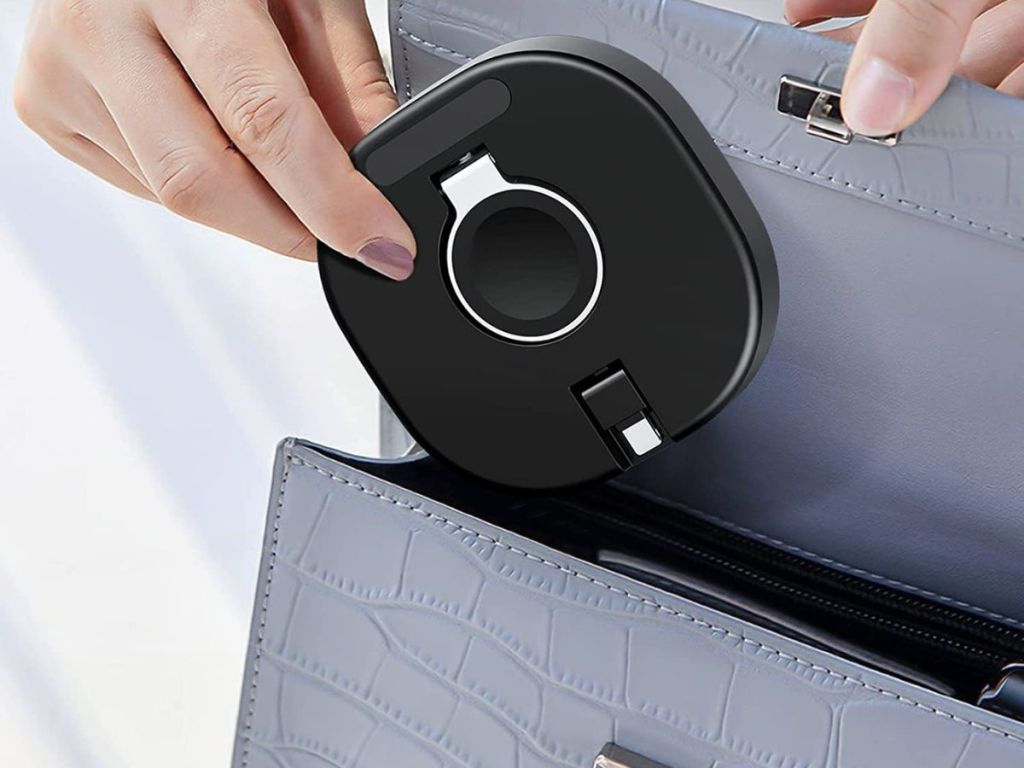 Apple Watch and Airpods Charger folded flat being tucked into a woman's purse